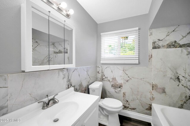 7039 N 15th St, Phoenix, AZ 85020 - bathroom featuring vanity, toilet, a washtub, wainscoting, and tile walls