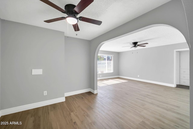 7039 N 15th St, Phoenix, AZ 85020 - unfurnished room with ceiling fan, arched walkways, wood finished floors, and baseboards