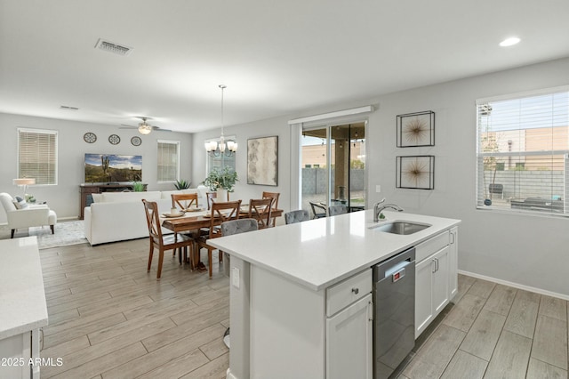 kitchen featuring wood finish floors, a sink, visible vents, open floor plan, and dishwasher