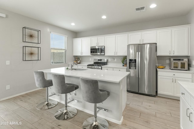 kitchen featuring stainless steel appliances, a sink, visible vents, and wood tiled floor