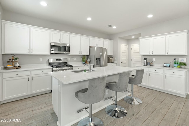 kitchen featuring stainless steel appliances, wood finish floors, a sink, and white cabinetry