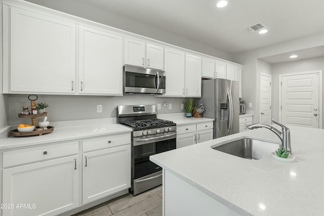 kitchen featuring recessed lighting, visible vents, appliances with stainless steel finishes, white cabinets, and a sink