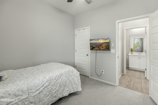 bedroom with light carpet, a sink, a ceiling fan, visible vents, and baseboards