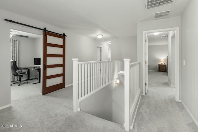 corridor featuring carpet, visible vents, an upstairs landing, and a barn door