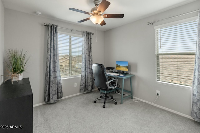 carpeted office space featuring baseboards and a ceiling fan