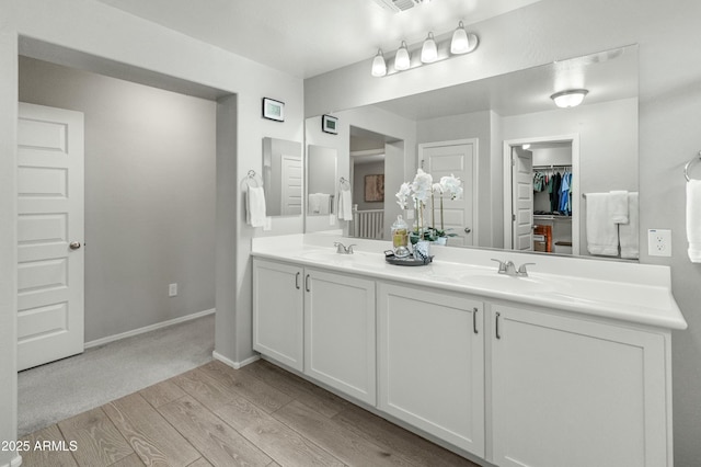 full bathroom with double vanity, wood finished floors, a sink, and baseboards