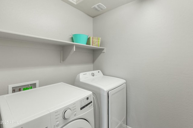 clothes washing area with laundry area, visible vents, and washer and clothes dryer