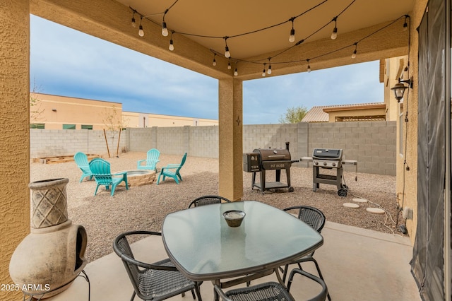 view of patio / terrace with an outdoor fire pit, grilling area, a fenced backyard, and outdoor dining space