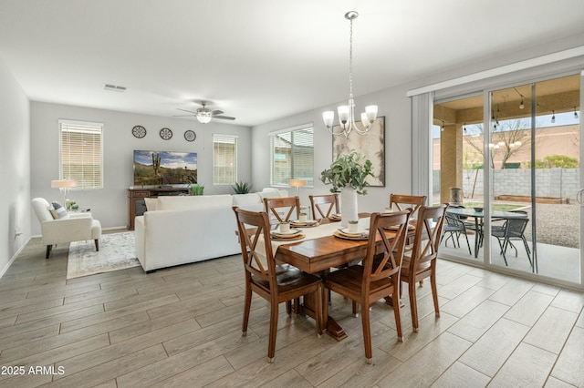 dining space with ceiling fan with notable chandelier, light wood finished floors, and visible vents