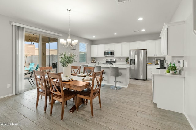 dining area with an inviting chandelier, wood tiled floor, baseboards, and recessed lighting