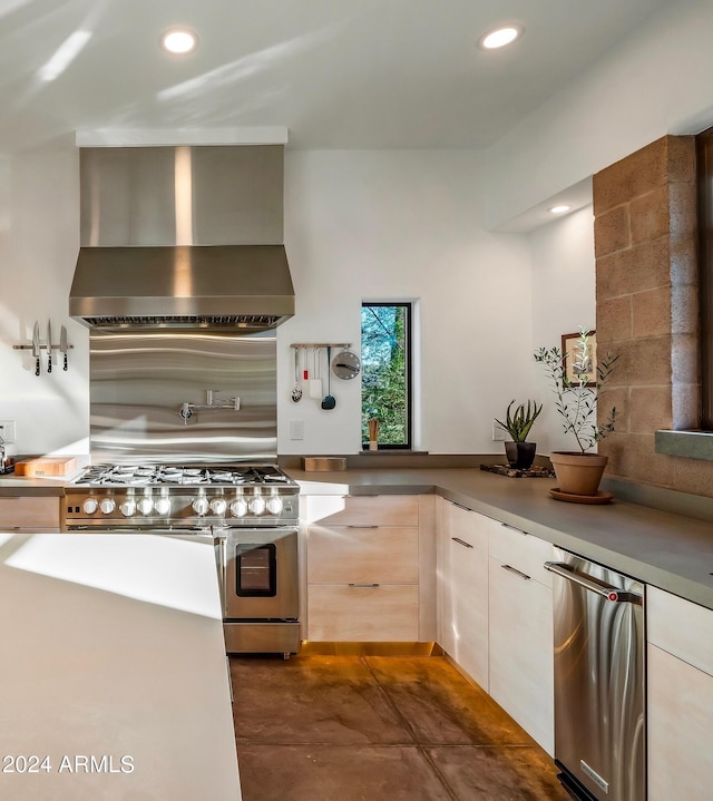 kitchen with dark tile patterned flooring, wall chimney exhaust hood, range with two ovens, and decorative backsplash