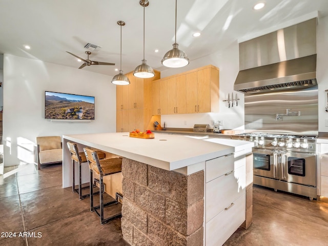 kitchen with range with two ovens, wall chimney exhaust hood, light brown cabinetry, and a center island