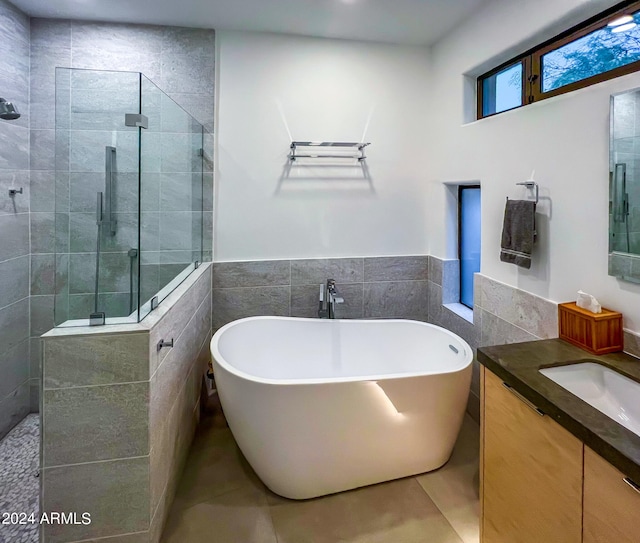 bathroom featuring independent shower and bath, vanity, and tile walls