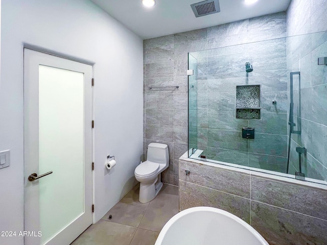 bathroom with tile walls, tile patterned flooring, toilet, and tiled shower