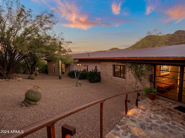 property exterior at dusk with a mountain view and a patio area