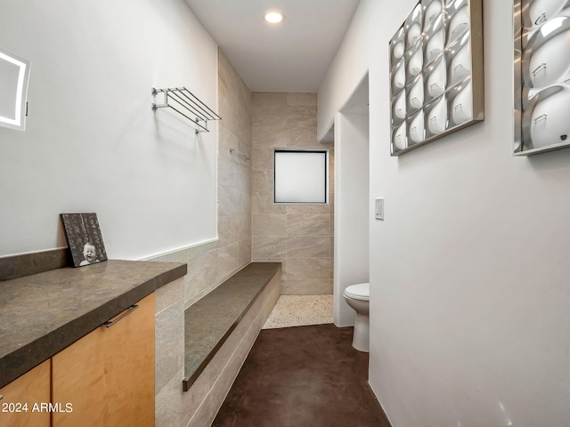 bathroom with toilet, vanity, concrete floors, and tiled shower