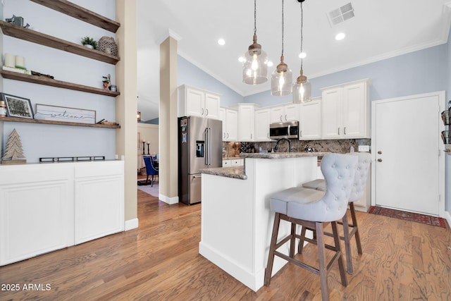 6708 W Utopia Rd, Glendale, AZ 85308 - kitchen featuring appliances with stainless steel finishes, ornamental molding, backsplash, a kitchen island, and a kitchen bar
