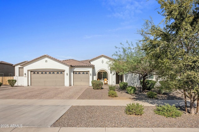 mediterranean / spanish house with an attached garage, a tile roof, decorative driveway, and stucco siding