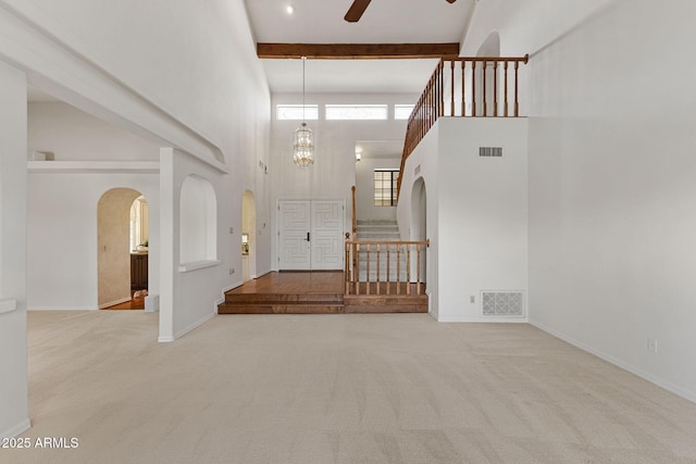 entryway featuring carpet floors, stairs, visible vents, and beam ceiling