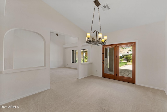 carpeted empty room with a wealth of natural light, lofted ceiling, a chandelier, and visible vents