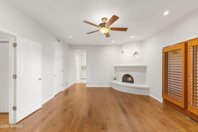 unfurnished living room with a lit fireplace, wood finished floors, and visible vents