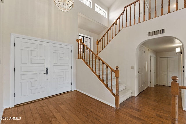 entryway with a towering ceiling, visible vents, arched walkways, and hardwood / wood-style floors