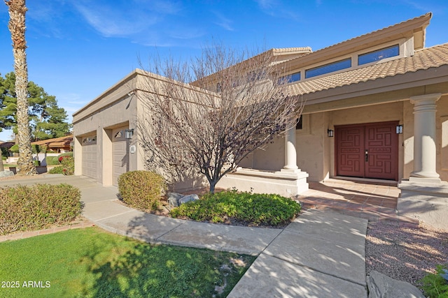 view of front facade featuring an attached garage, a tile roof, and stucco siding