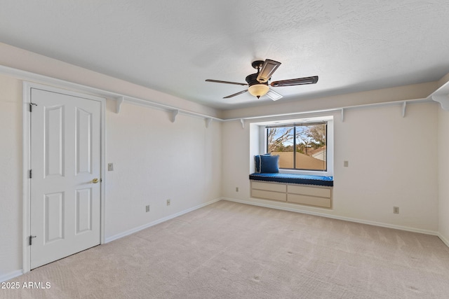 unfurnished bedroom featuring a ceiling fan, light colored carpet, a textured ceiling, and baseboards