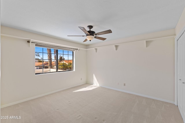 carpeted spare room with ceiling fan and baseboards