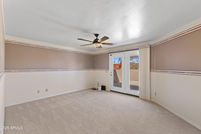 carpeted spare room with ceiling fan, baseboards, and a textured ceiling