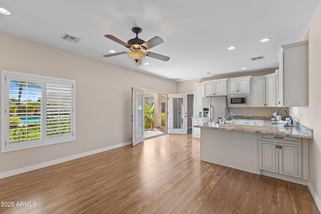 kitchen featuring a peninsula, appliances with stainless steel finishes, a sink, and visible vents