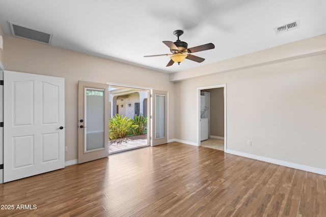 unfurnished room featuring wood finished floors, visible vents, and baseboards