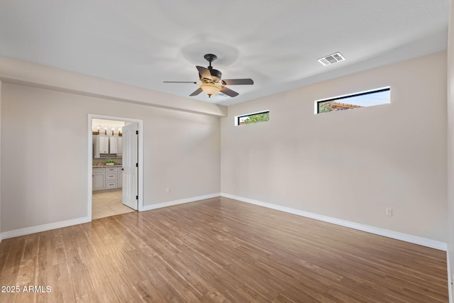 empty room featuring light wood-type flooring, baseboards, visible vents, and a ceiling fan