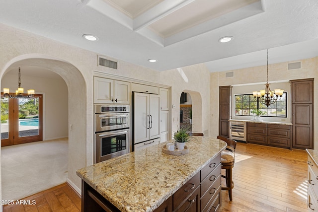 kitchen with paneled built in refrigerator, a chandelier, beverage cooler, and arched walkways