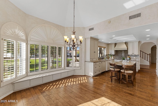 unfurnished dining area featuring arched walkways, a sink, dark wood finished floors, and visible vents