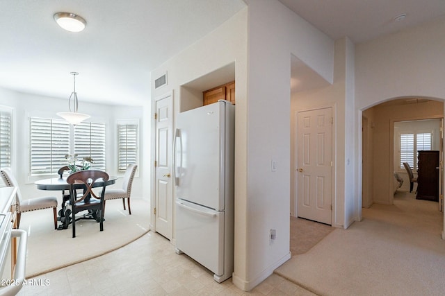 kitchen with pendant lighting, white fridge, a wealth of natural light, and light colored carpet