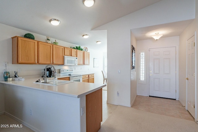 kitchen featuring sink, kitchen peninsula, vaulted ceiling, white appliances, and light tile patterned floors