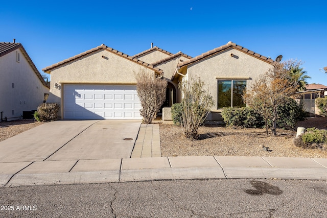 mediterranean / spanish home featuring concrete driveway, a tiled roof, an attached garage, and stucco siding