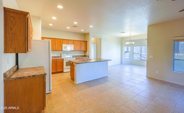 kitchen with brown cabinets, open floor plan, a sink, an island with sink, and white appliances