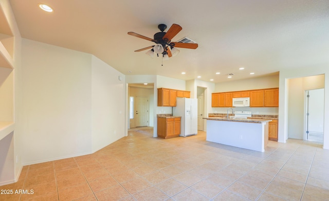 kitchen featuring recessed lighting, visible vents, a kitchen island with sink, light stone countertops, and white appliances