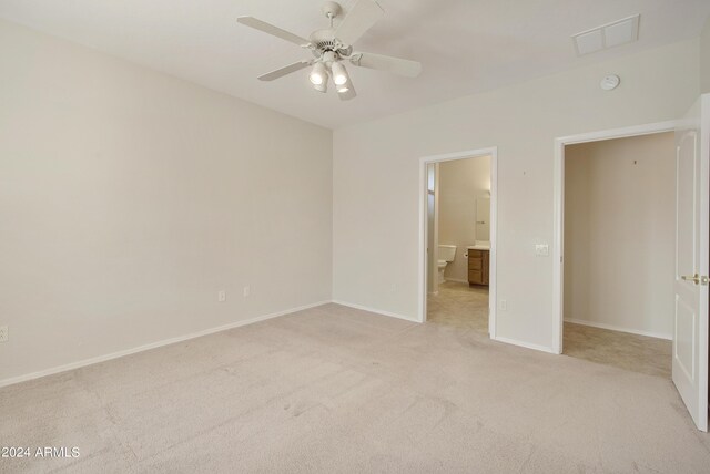 unfurnished bedroom with connected bathroom, ceiling fan, and light colored carpet