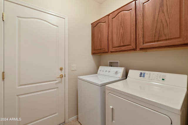 clothes washing area with washer and clothes dryer and cabinets