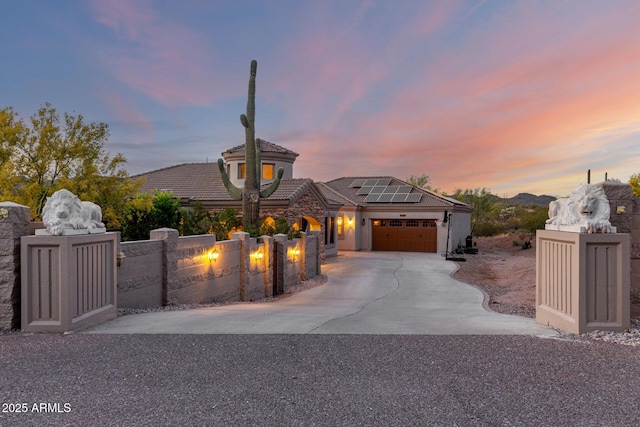 french country home featuring driveway, a tile roof, a garage, fence, and roof mounted solar panels