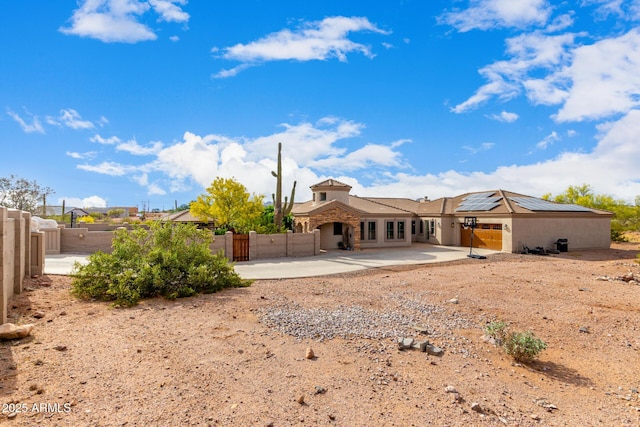 back of property featuring solar panels, a fenced backyard, a patio area, and stucco siding