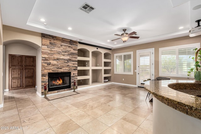 living room with a raised ceiling, recessed lighting, and visible vents