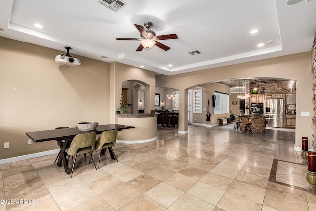 dining space with recessed lighting, a raised ceiling, arched walkways, and visible vents