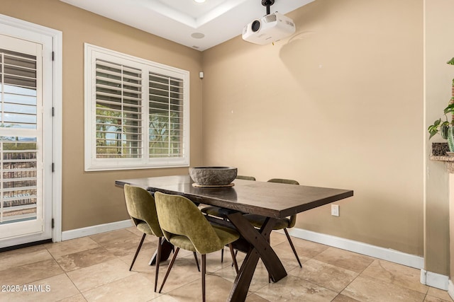 dining area with baseboards and a tray ceiling