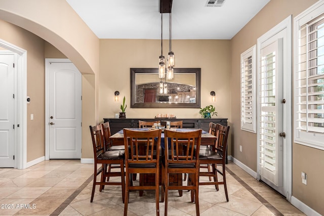 dining space with baseboards, arched walkways, light tile patterned floors, and visible vents