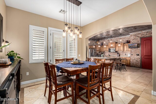 dining room with arched walkways, baseboards, visible vents, and light tile patterned floors