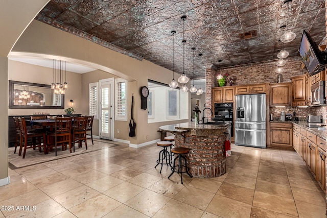 kitchen featuring an inviting chandelier, a sink, an ornate ceiling, arched walkways, and stainless steel appliances